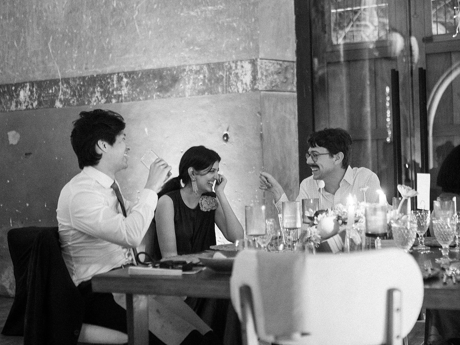 Cuatro personas sonrientes en una mesa de celebración con comida y velas, compartiendo risas en un entorno social.