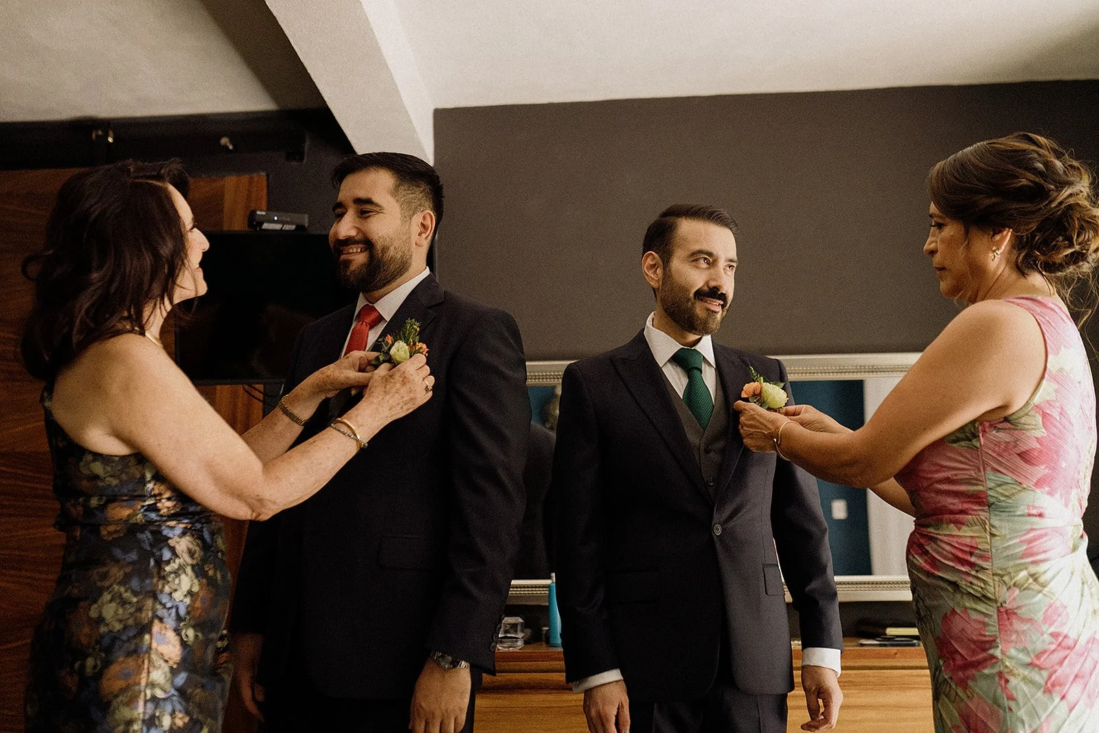 Pareja celebrando su boda con familiares colocando corsages en sus trajes en una ceremonia en interiores