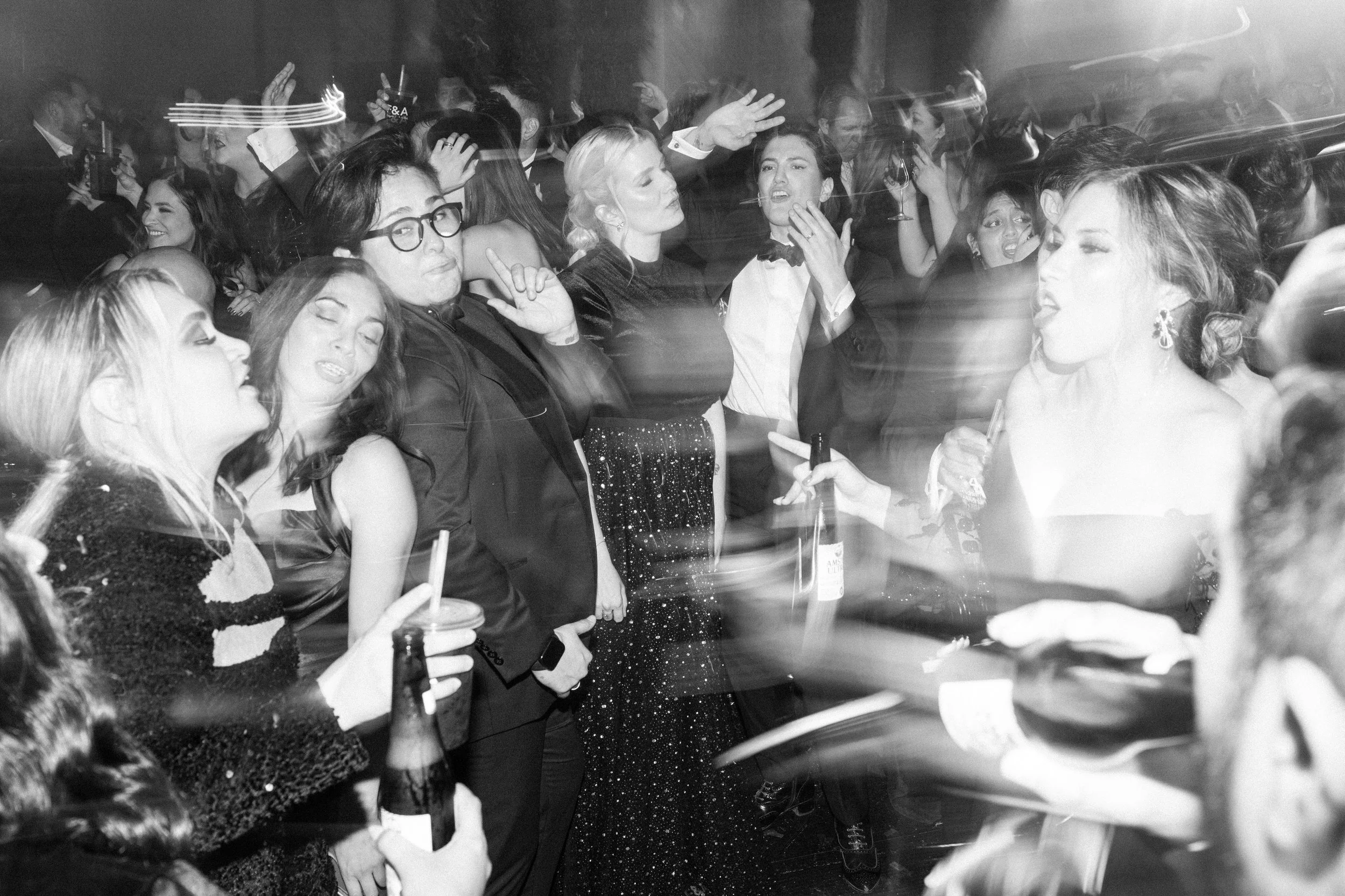 Personas en una fiesta social disfrutando y bailando en un ambiente con iluminación tenue.