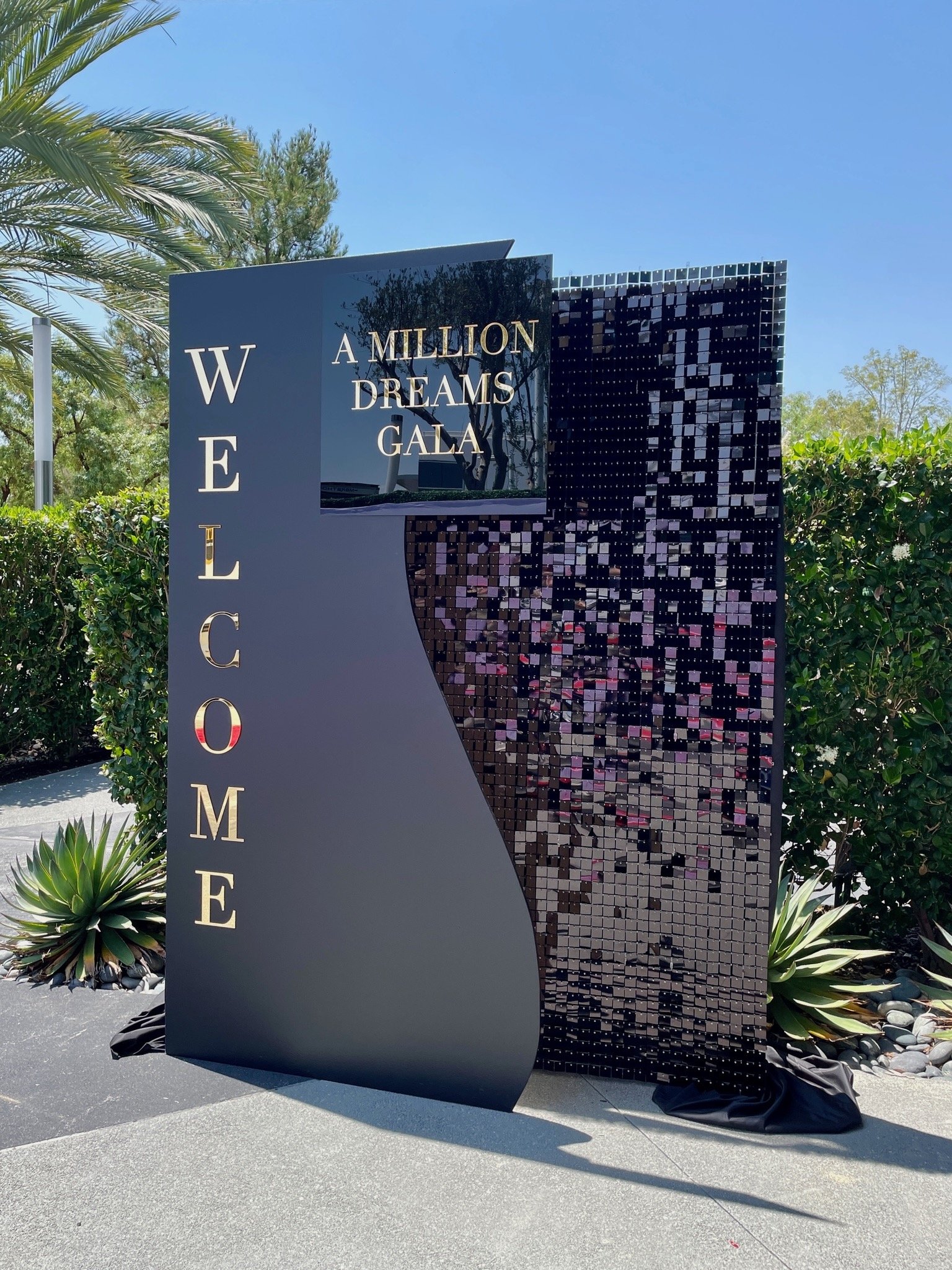 Decorative sign with 'Welcome' and 'A Million Dreams Gala' text against a black shimmer wall and custom backdrop.