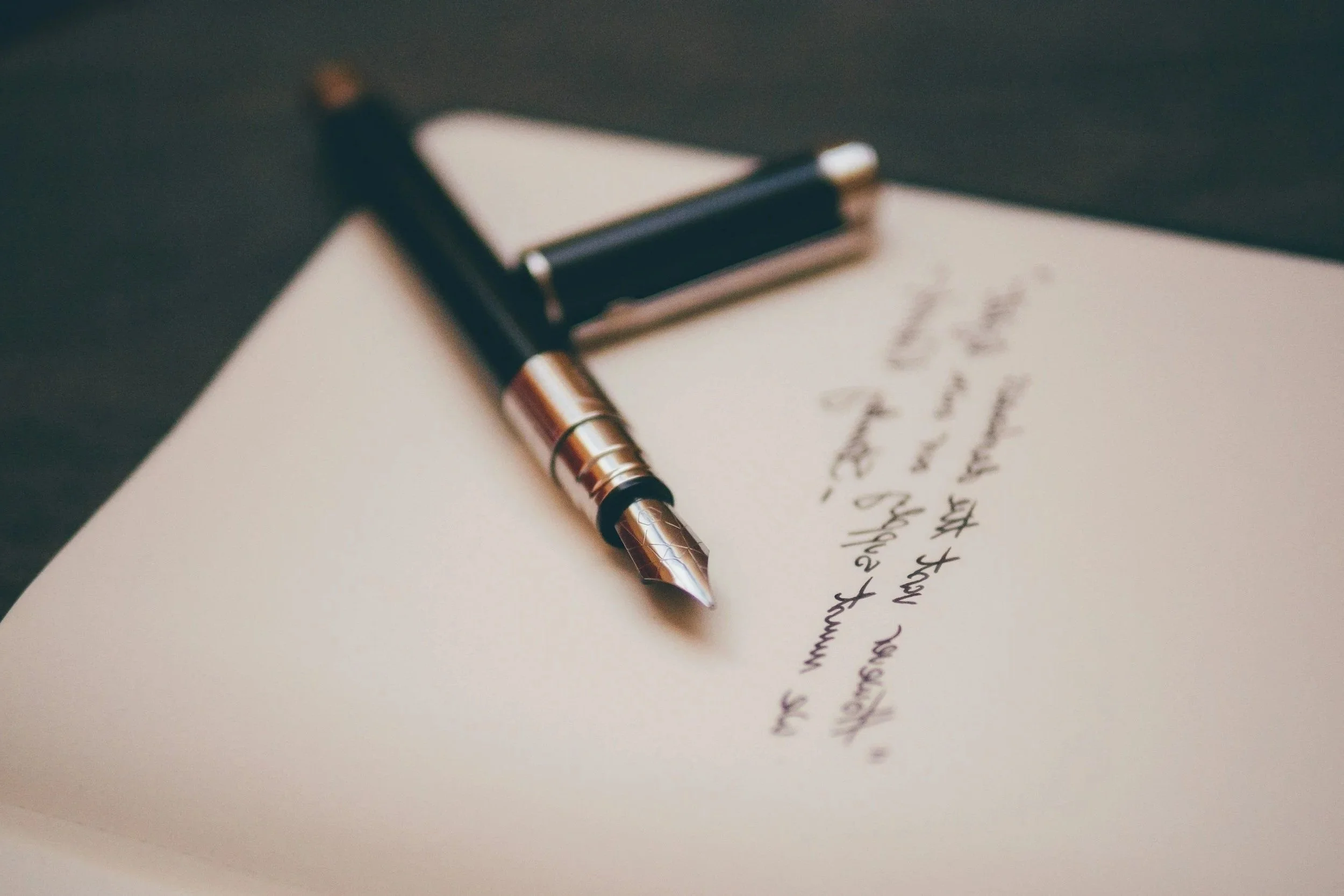 Close-up of a fountain pen resting on handwritten notes on paper.