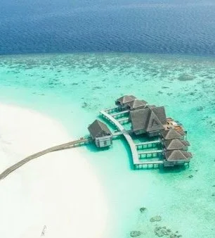 Overwater bungalows on a private island with white sandy beach and clear turquoise water.