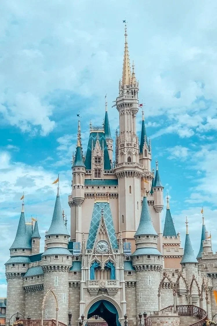 Disney castle with tall spires and a cloudy sky in the background.