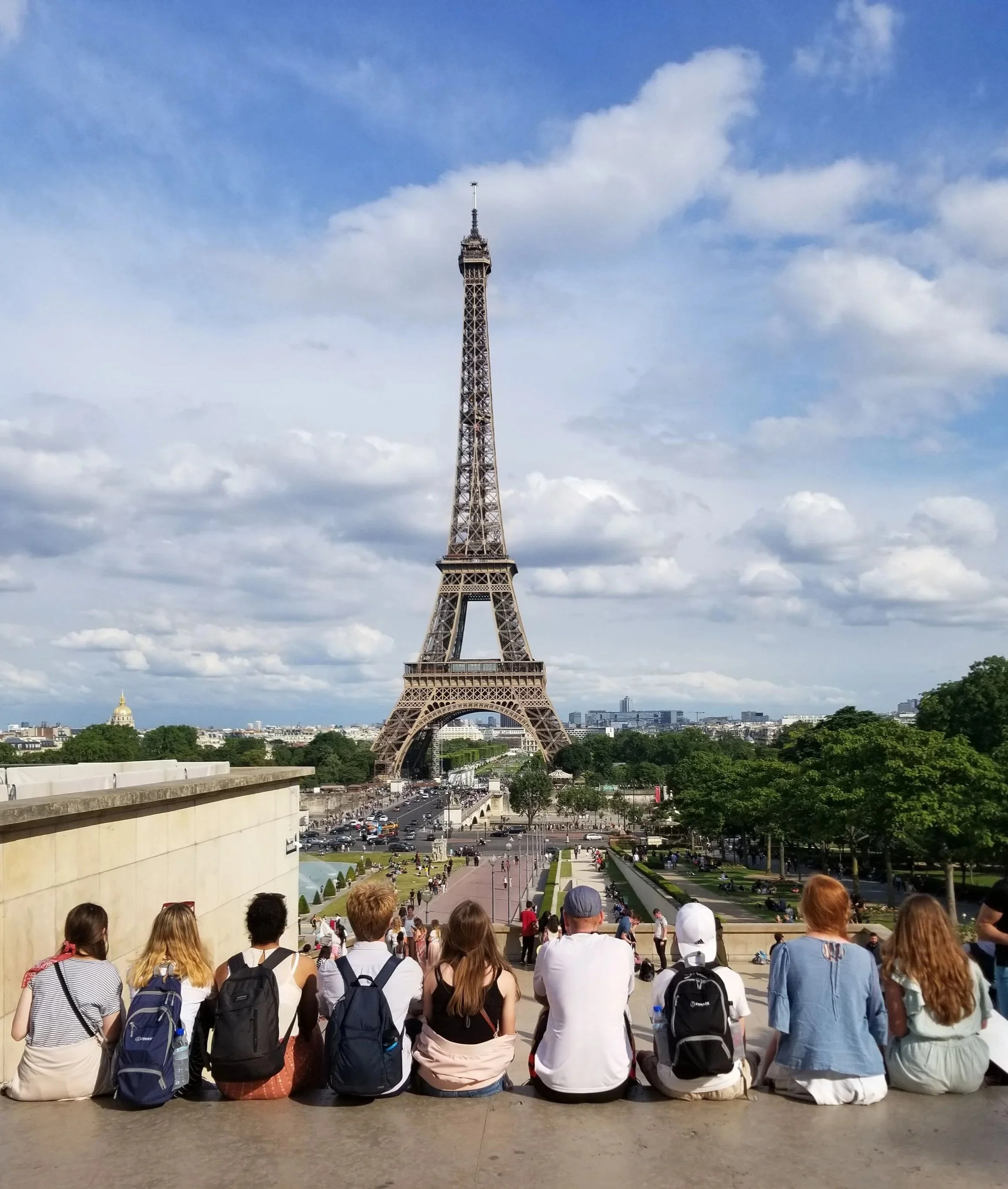 Group of people sitting and standing at the Trocadéro Gardens with the Eiffel Tower in the background, in Paris, France.