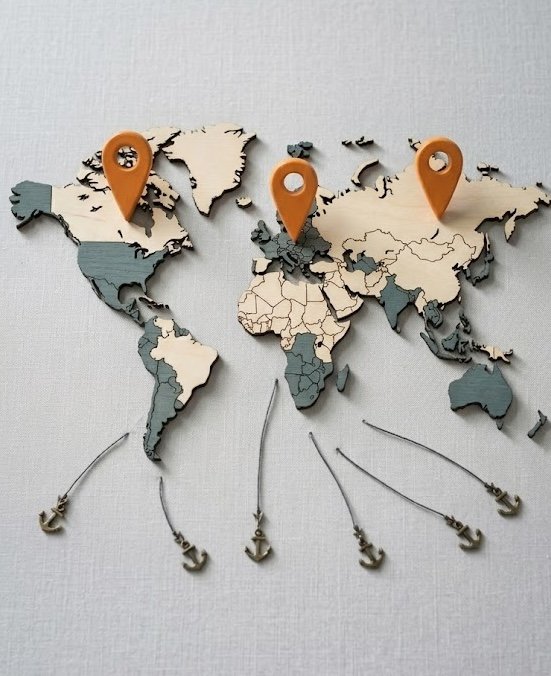 Wooden world map with three orange location markers and six small anchors dangling below.
