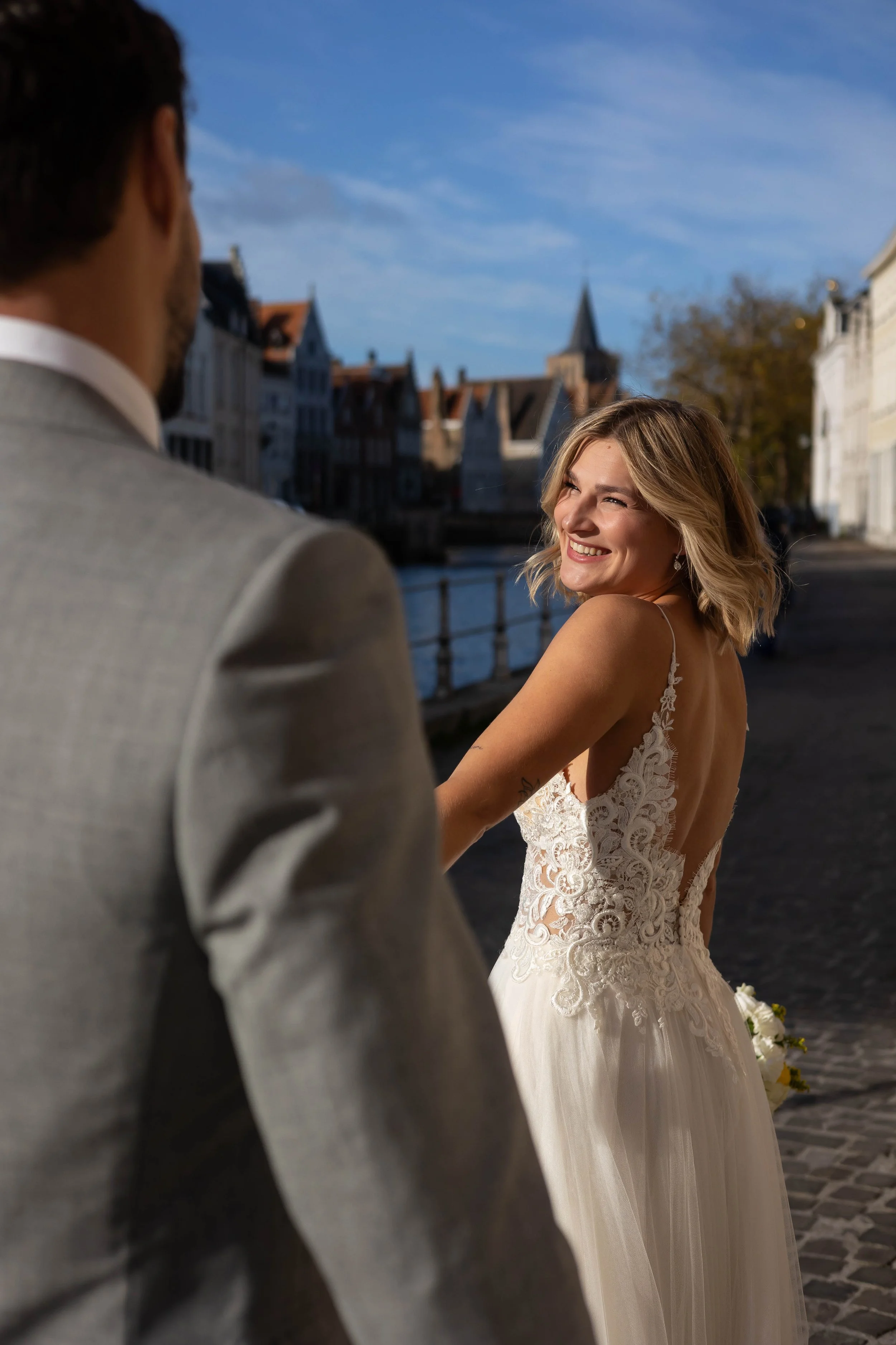 Bride laughing with groom on cobblestone street in Bruges, Belgium
