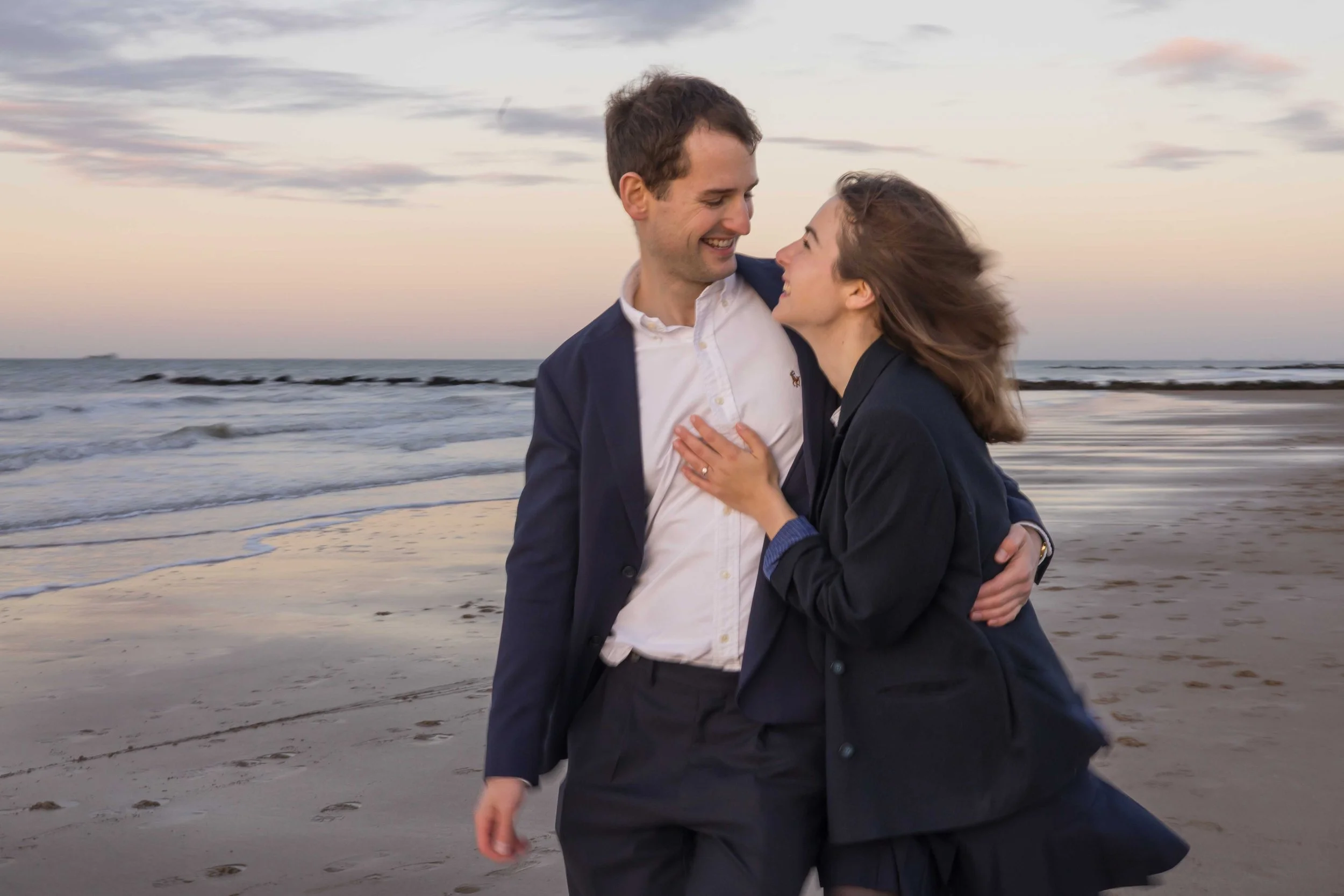 A blurry photo of a man and woman smiling and touching. Beach Knokke-Heist, België. Engagement shoot at sunset.