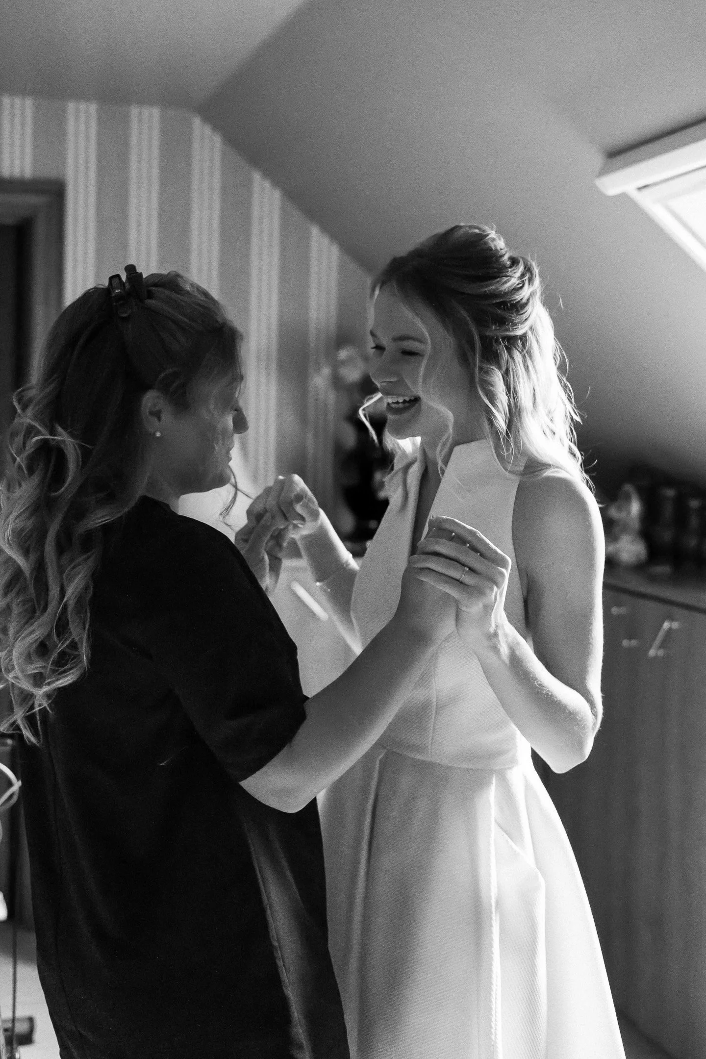 Bride and maid of honour laughing and crying. Black and white photo
