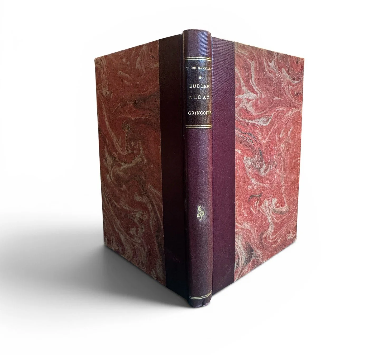 A red and black hardcover book with gold lettering on the spine, placed inside a marbled red slipcase.