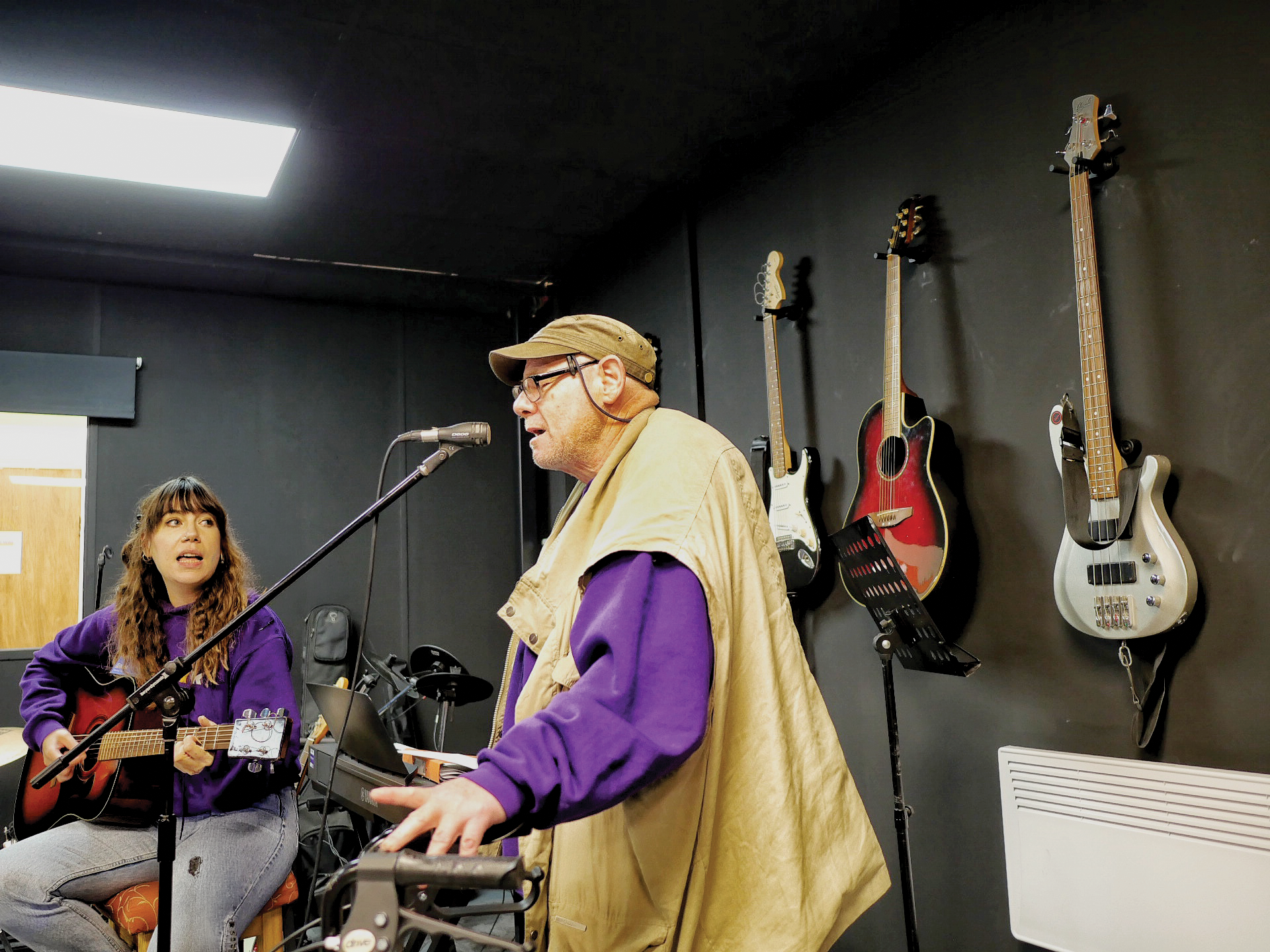 Key's music therapist plays guitar and accompanies a service user, a man with an acquired brain injury, who is singing in Key's black box studio.
