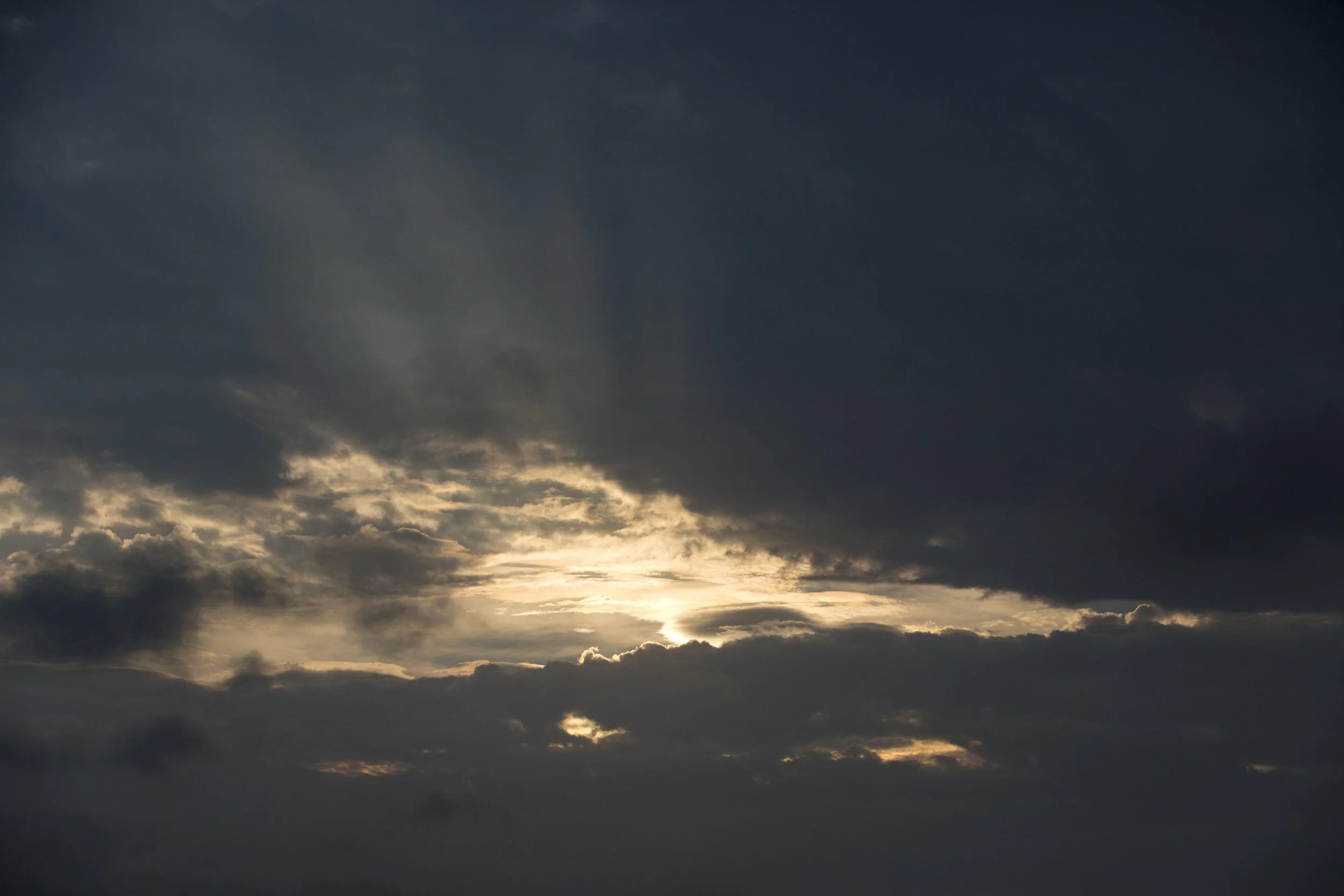 Ciel nuageux avec des rayons de soleil perçant à travers les nuages.