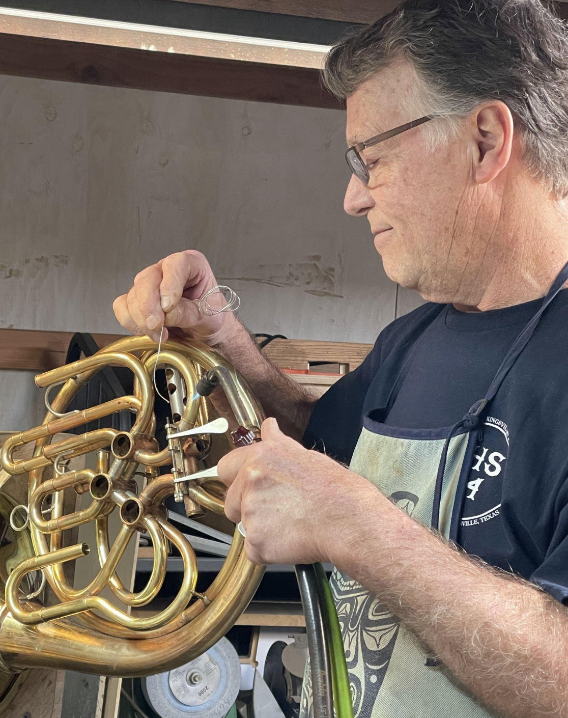 Bruce Roberts working on a French horn in a workshop setting.