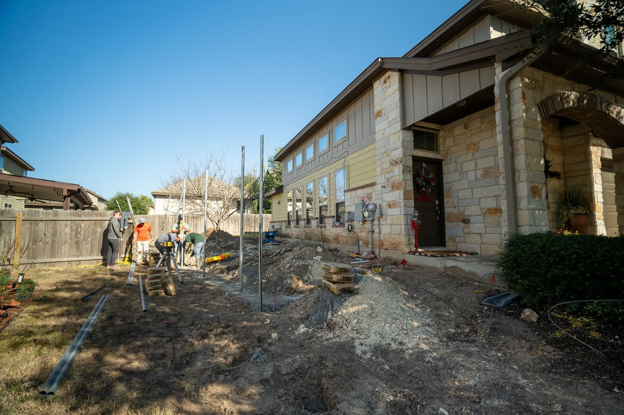 Construction workers digging and working on the ground in the backyard of a house under renovation or landscaping project.