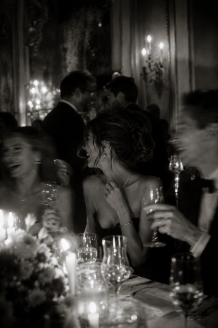 People socializing and laughing at a formal event or party with dim lighting and candles.