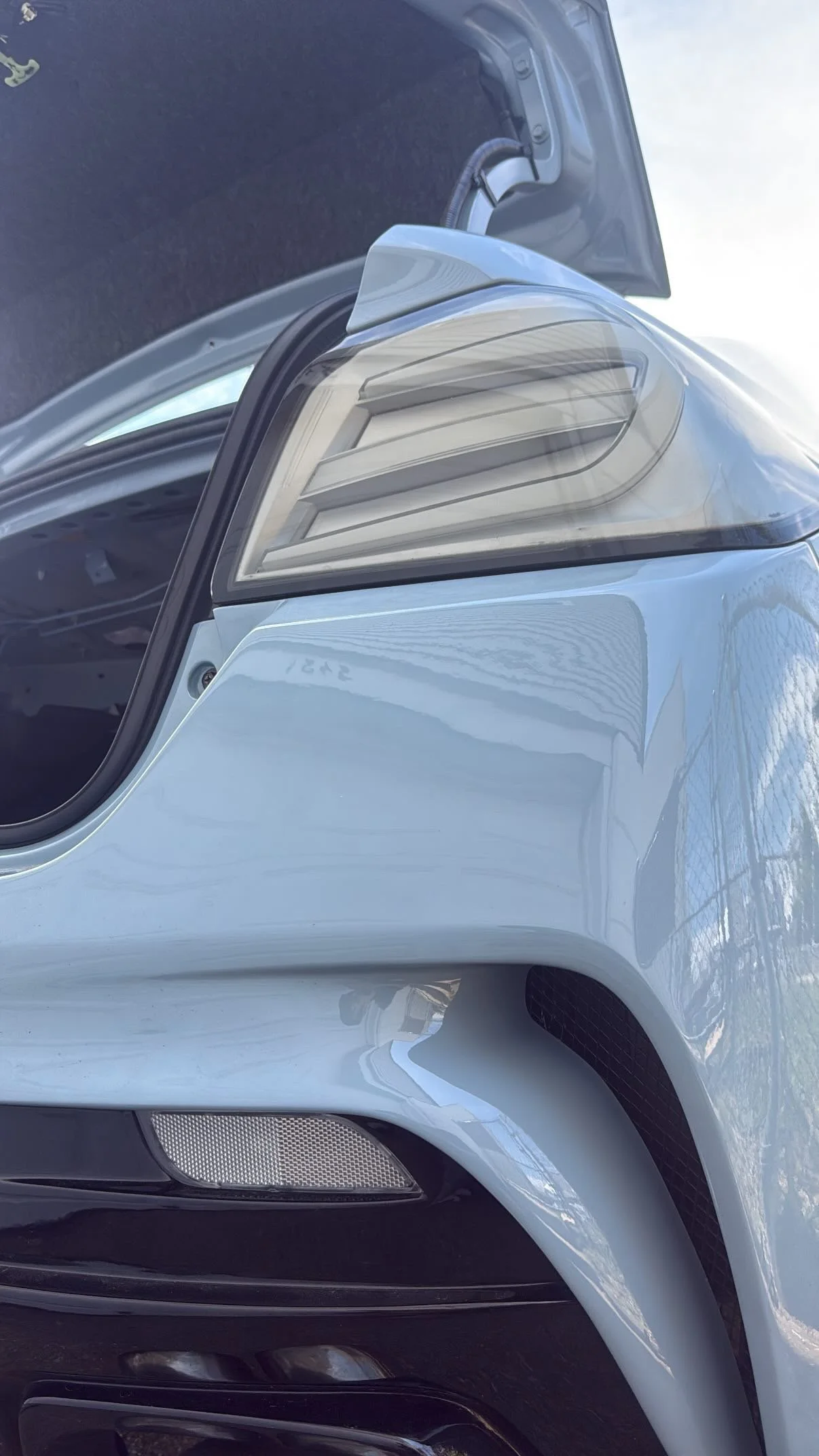 Close-up view of the front end of a silver car, showing the headlight, grille, and part of the hood.