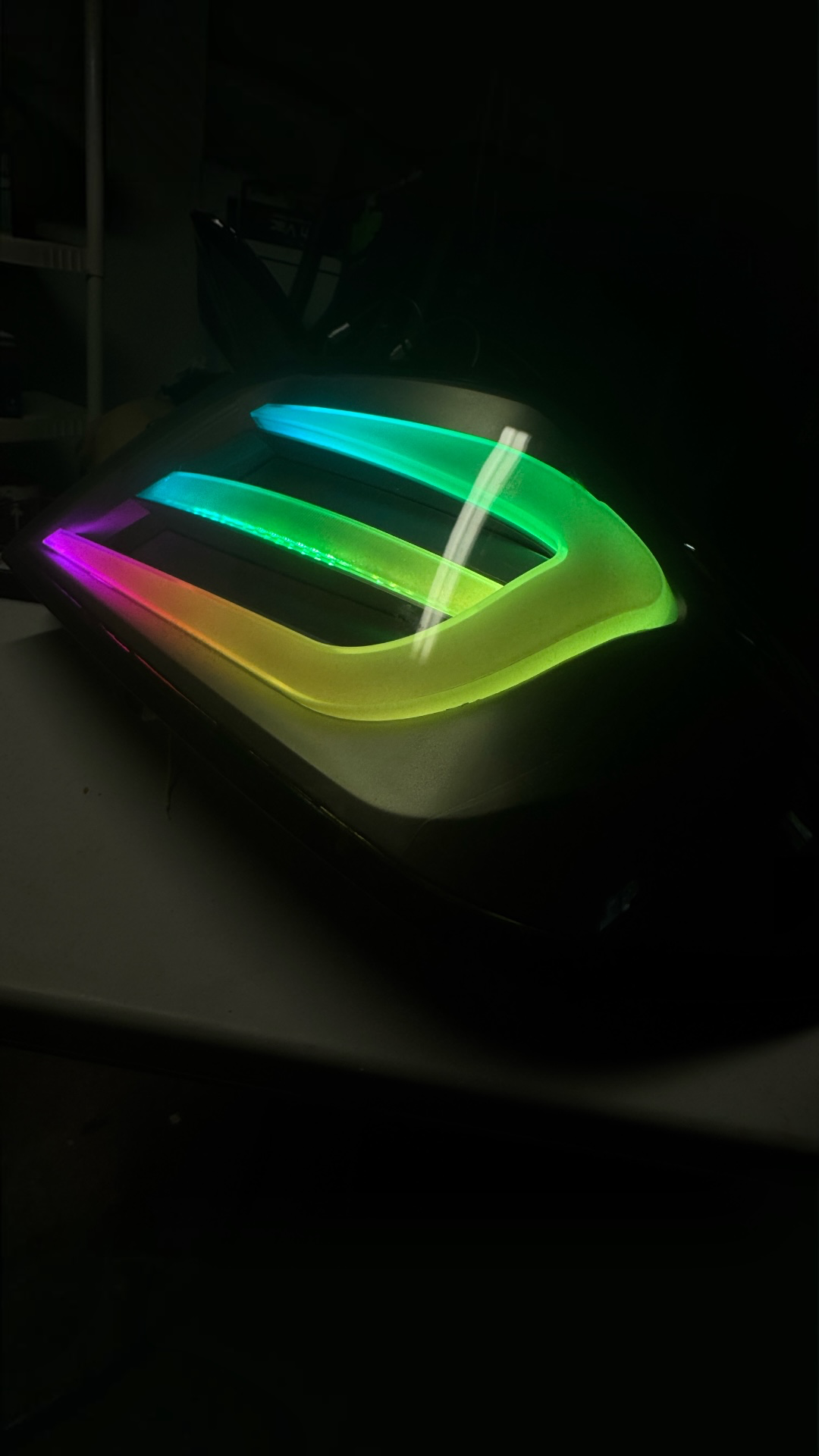 A dark-colored robotic vacuum cleaner with colorful LED lights on top.