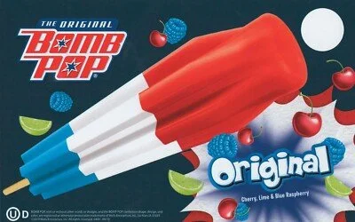 A Bomb Pop ice pop with red, white, and blue flavors surrounded by berries and lime slices, labeled as Original flavor.