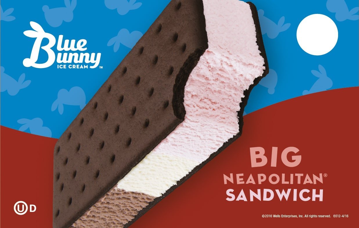 A large ice cream bar with three layers of different flavors, including chocolate, pink, white, and brown, in a partially opened wrapper with a blue and red background and the text 'Big Neapolitan Sandwich'.