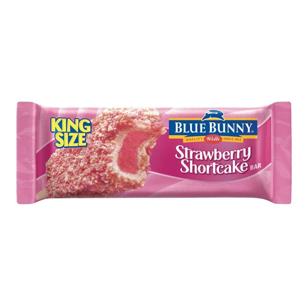 A pink package of King Size Blue Bunny Strawberry Shortcake ice cream bar, showing a close-up of the ice cream with pink and white layers.