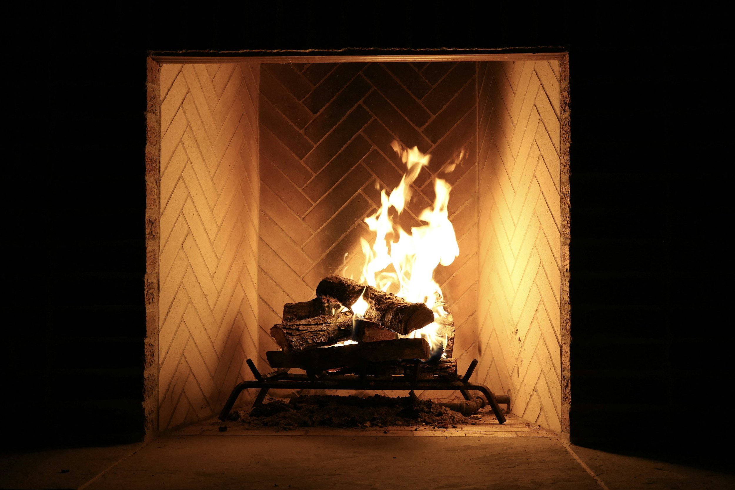 Gas fireplace with gas logs and warm flames behind a screen