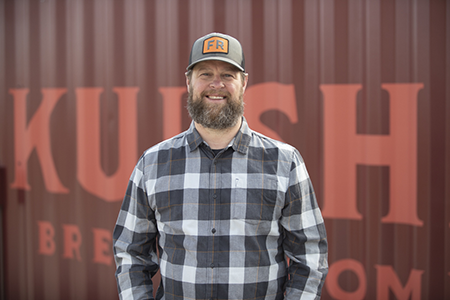 Matt standing in front of a red container with large orange letters.