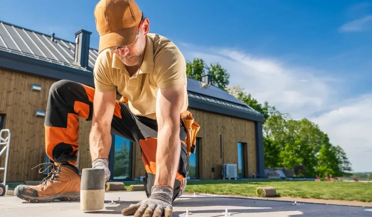 Construction worker leveling and tapping down flooring with a mallet during a home leveling project