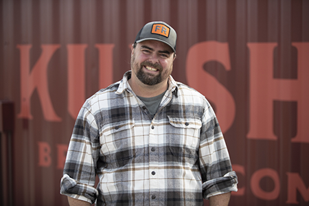 Eric in front of a red container with large partially visible letters.