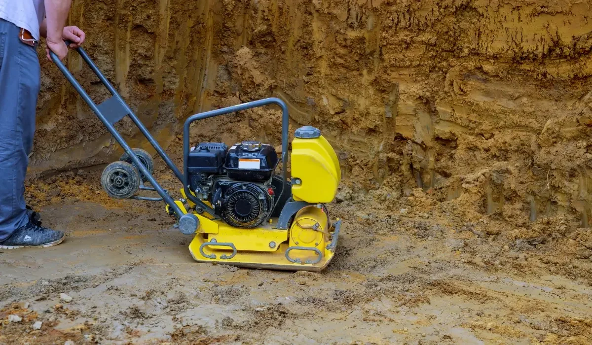 Plate compactor packing soil to reduce foundation movement