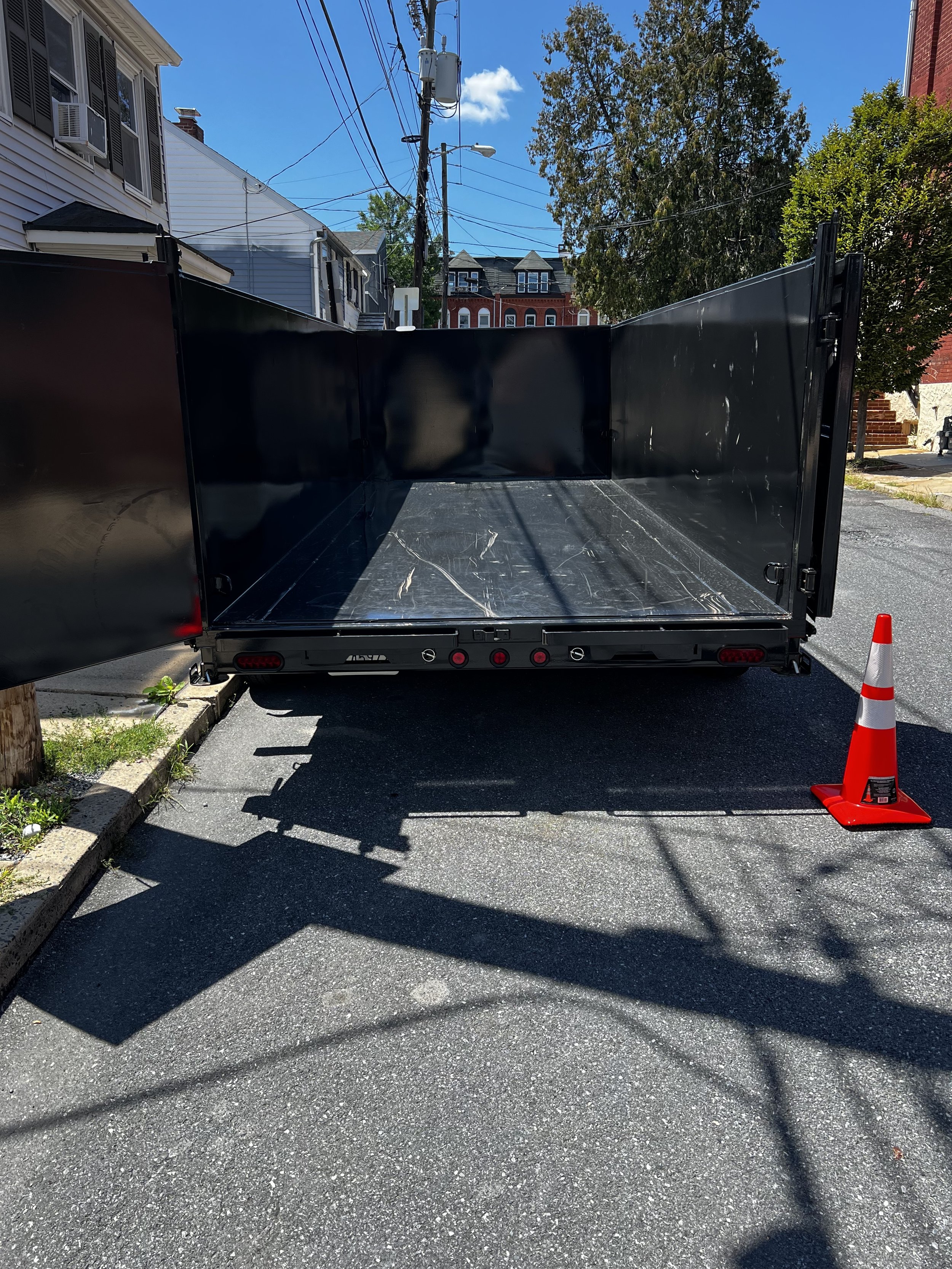 The empty rear view of a 7' by 16' dump trailer with 4' high side walls. Showing capacity of the dump trailer to haul junk. 
