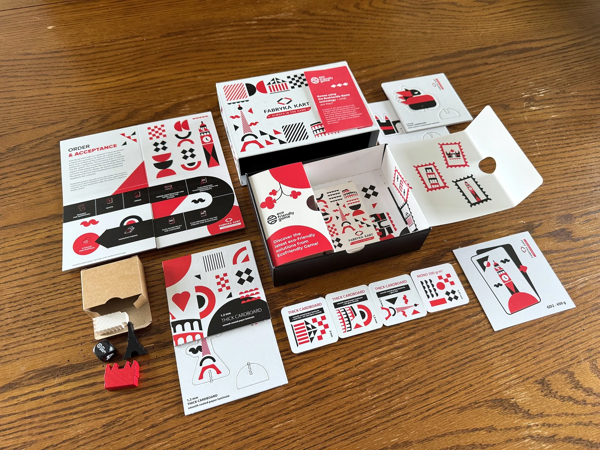 Photo of the contents of a manufacturing sample box from Fabryka Cart with varied paper thicknesses and wood game pieces.