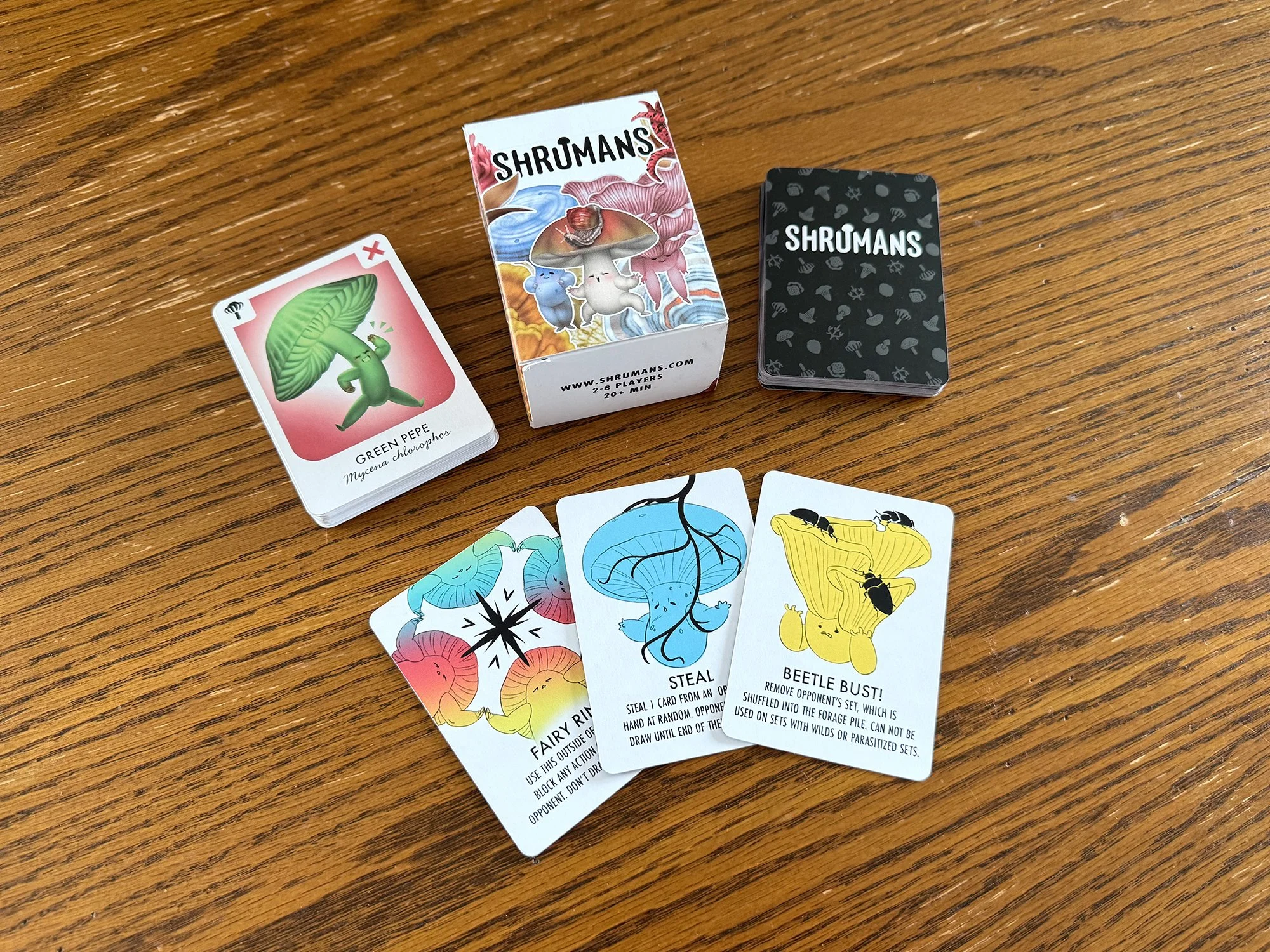 Photo of a Shrumans Card Game Prototype with a card box and selection of cards including main Shruman cards and action cards.