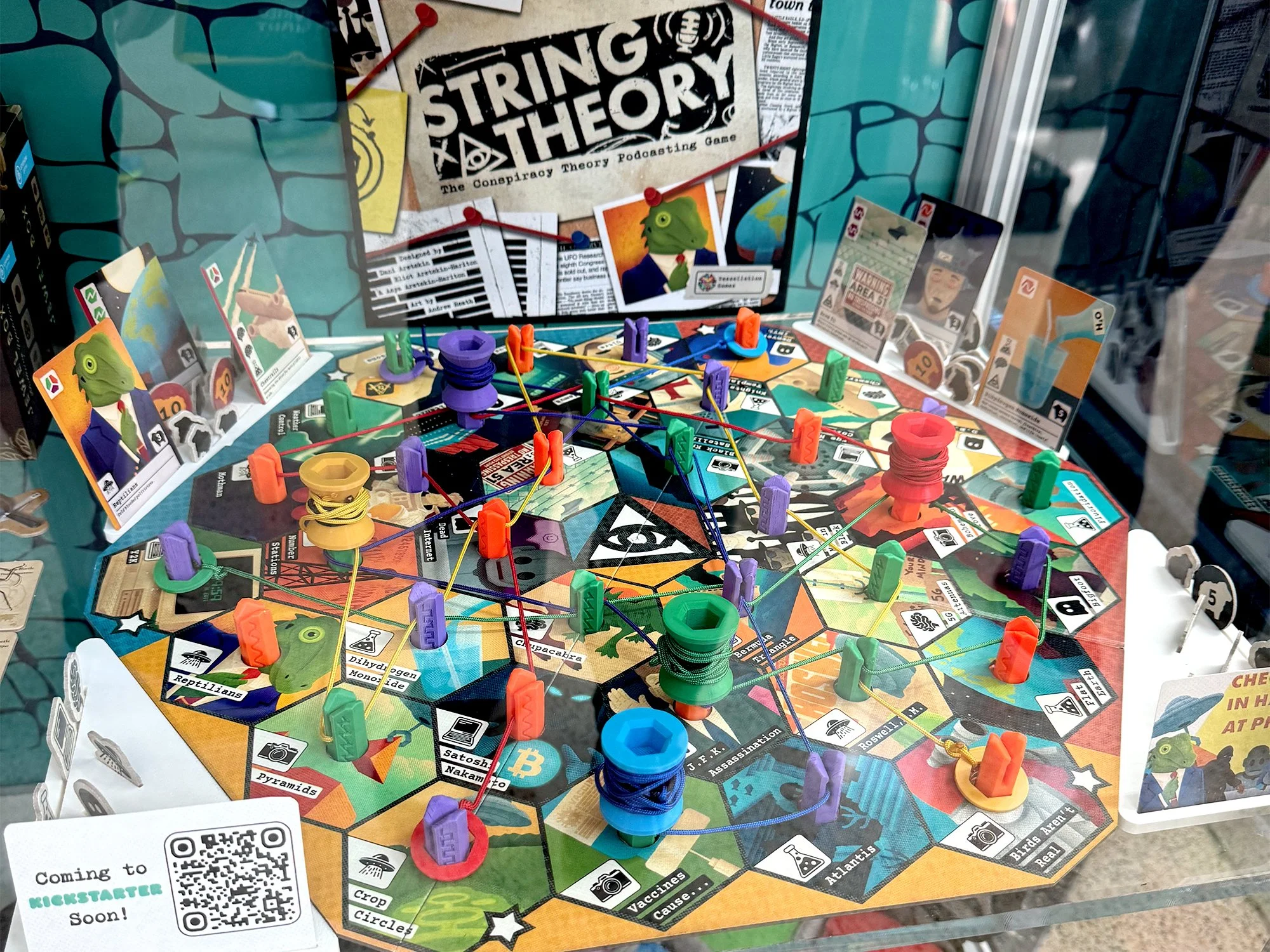 Photo of a board game called "String Theory" made of a board with connecting hexagon shapes and dowels with strings.