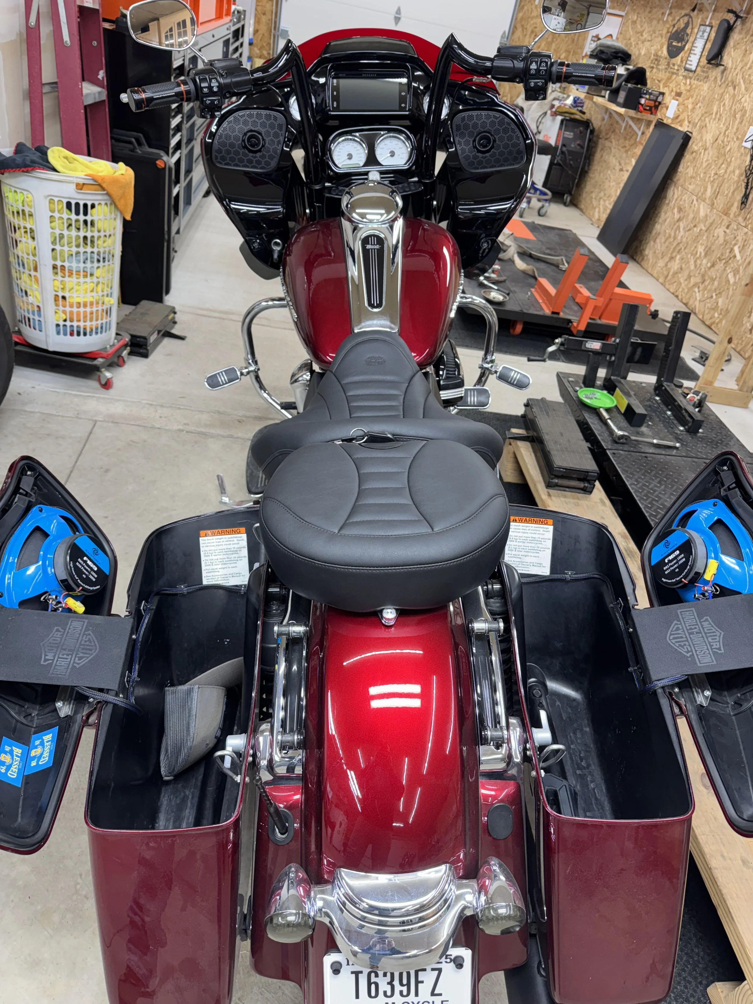Front view of a red Harley Davidson trike motorcycle in a garage with tools and equipment around.