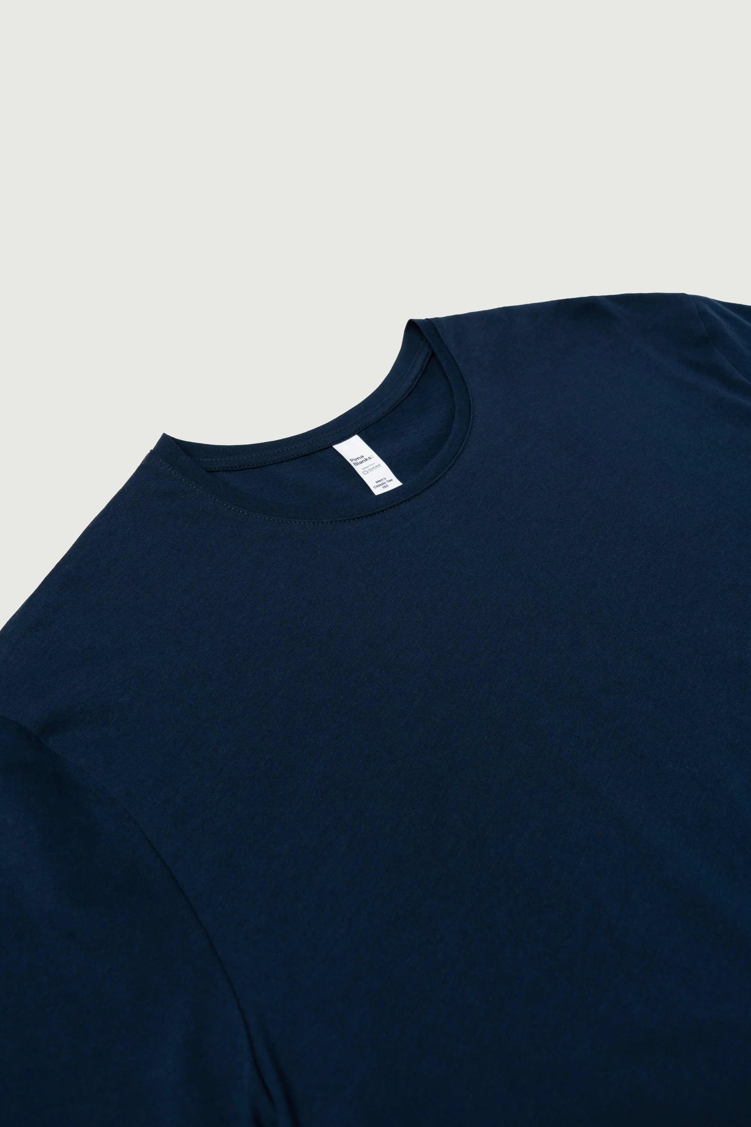 Close-up of a navy blue t-shirt with a round neckline, laid flat on a light-colored surface.