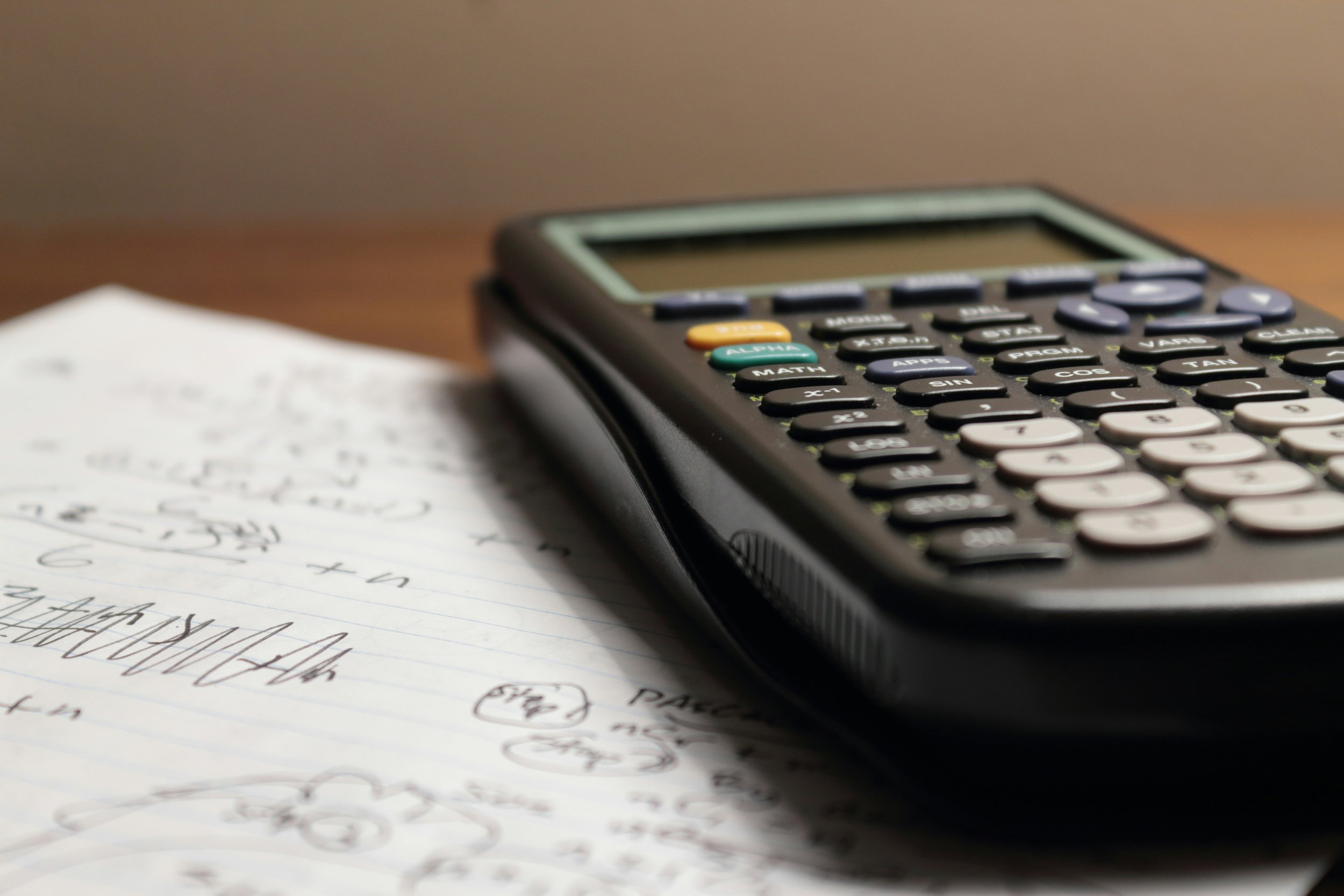 A calculator resting on paper with handwritten calculations.