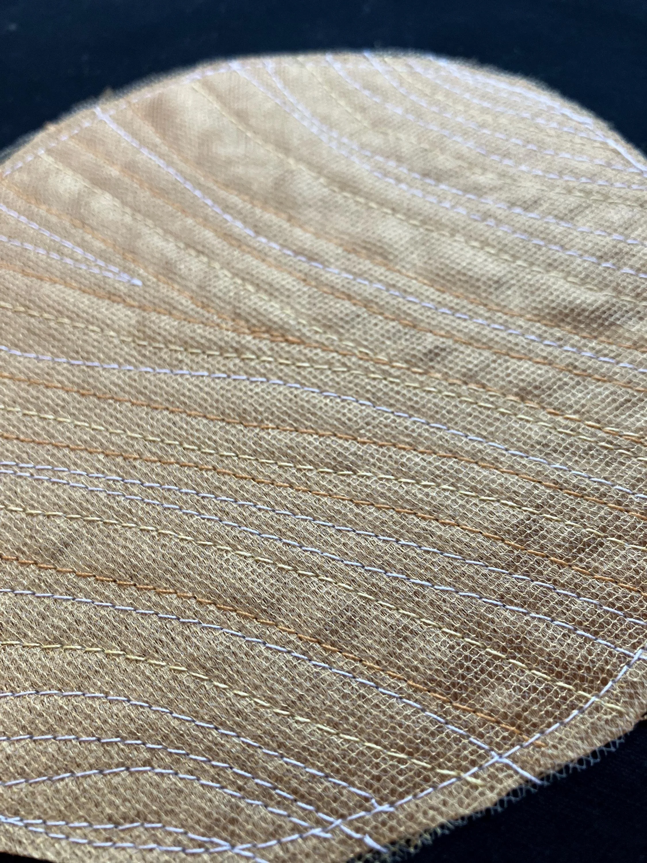Close-up view of a beige mesh fabric with embroidered lines, possibly a piece of clothing or decorative textile.