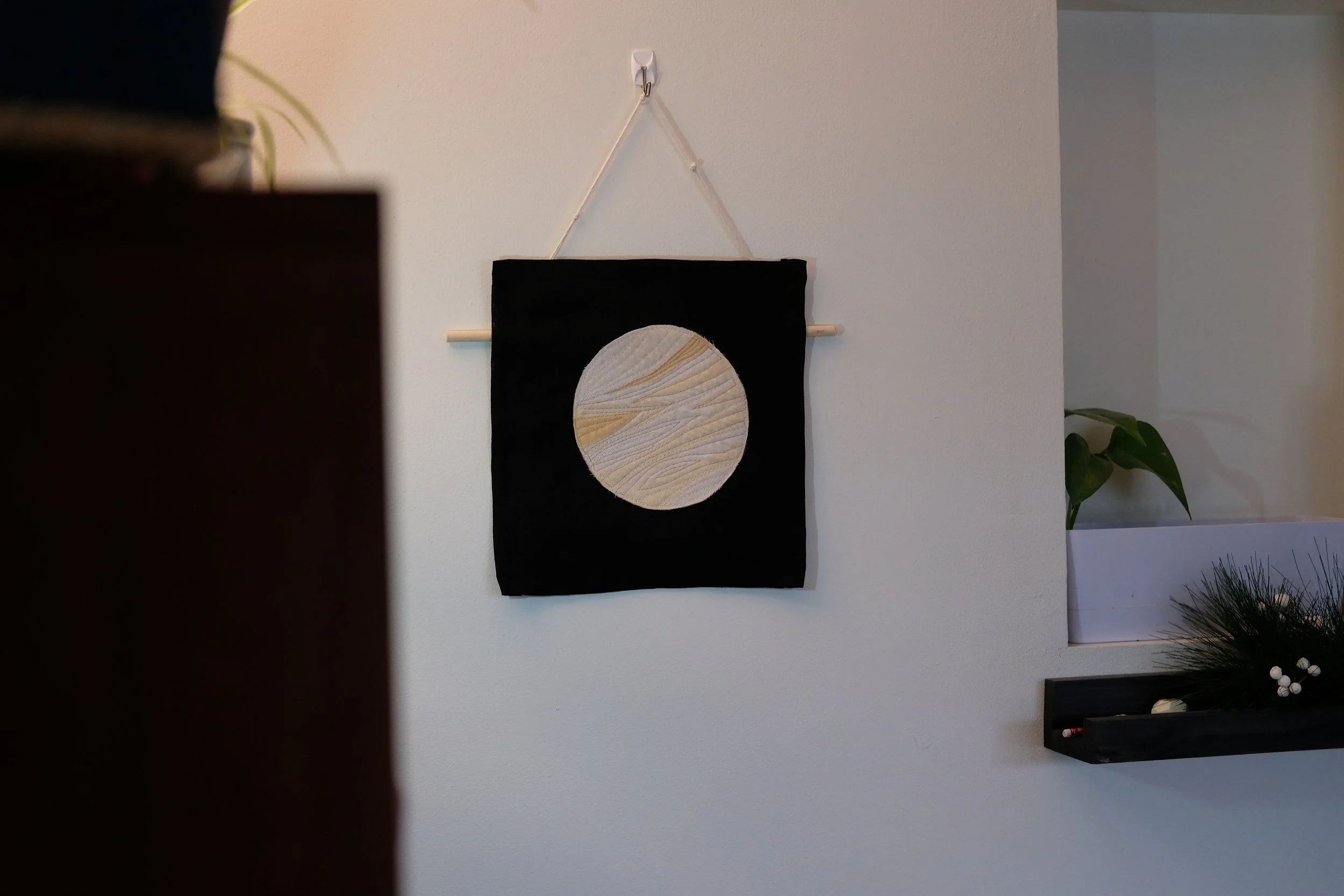 Fabric collage wall hanging of the planet venus in gold, cream, and white