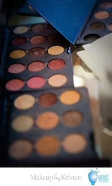Open eyeshadow palettes with various shades of eyeshadow in round pans, featuring colors like brown, pink, beige, and yellow on a makeup table.