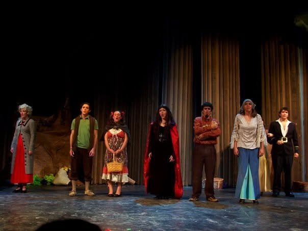 People standing on a stage after a theatrical performance.