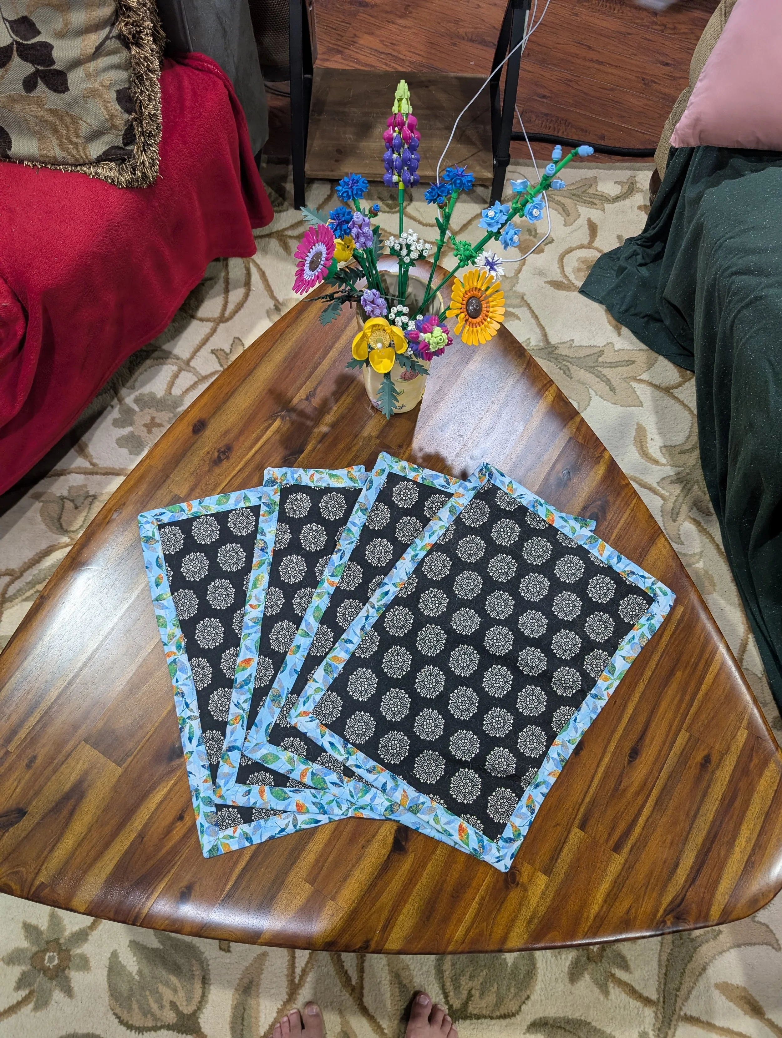 Four placemats with black and white patterns, and a light blue border, in a playing card spread.