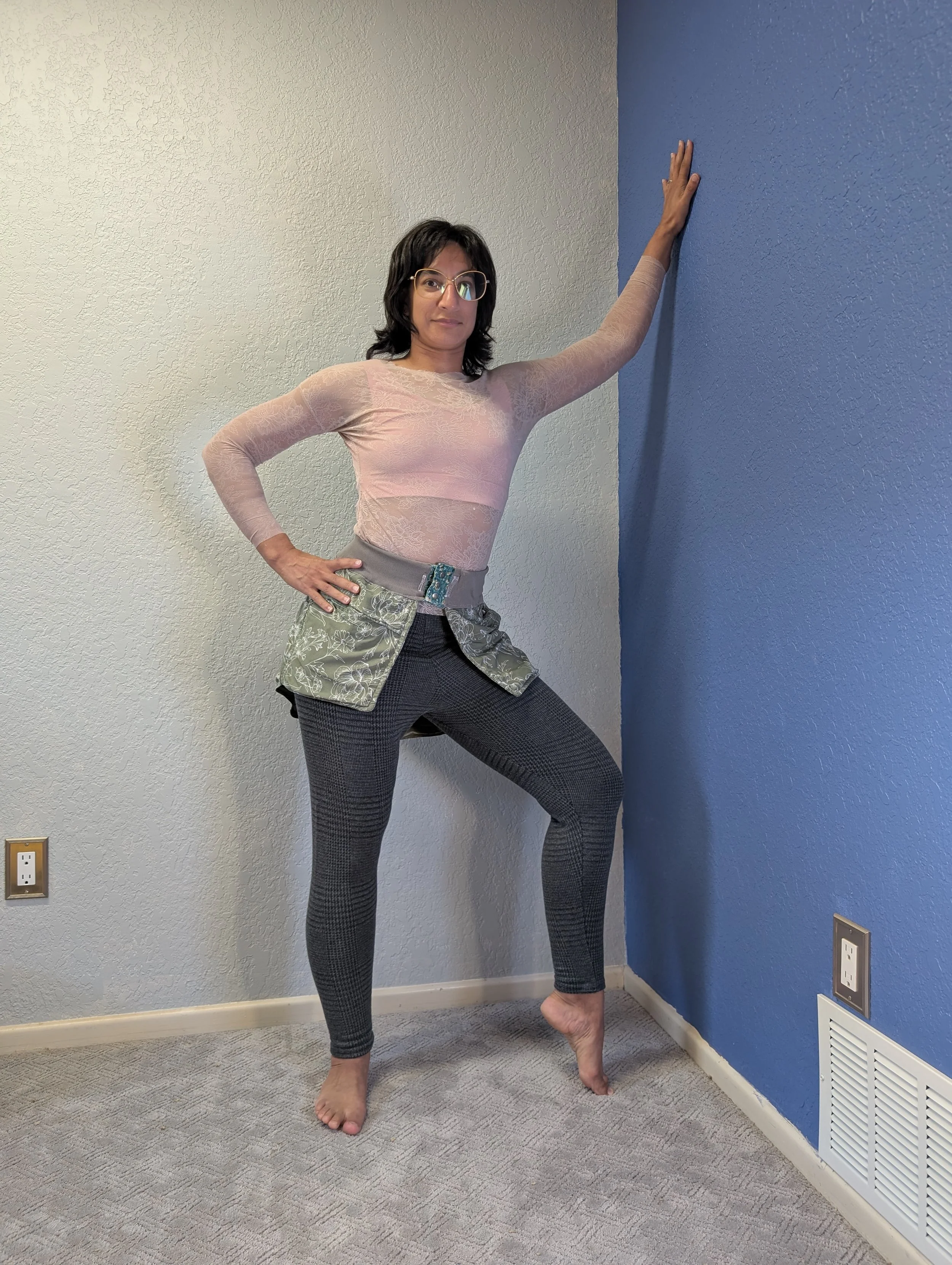 Woman posing while wearing a pink lace top, and subtle plaid skinny pants.