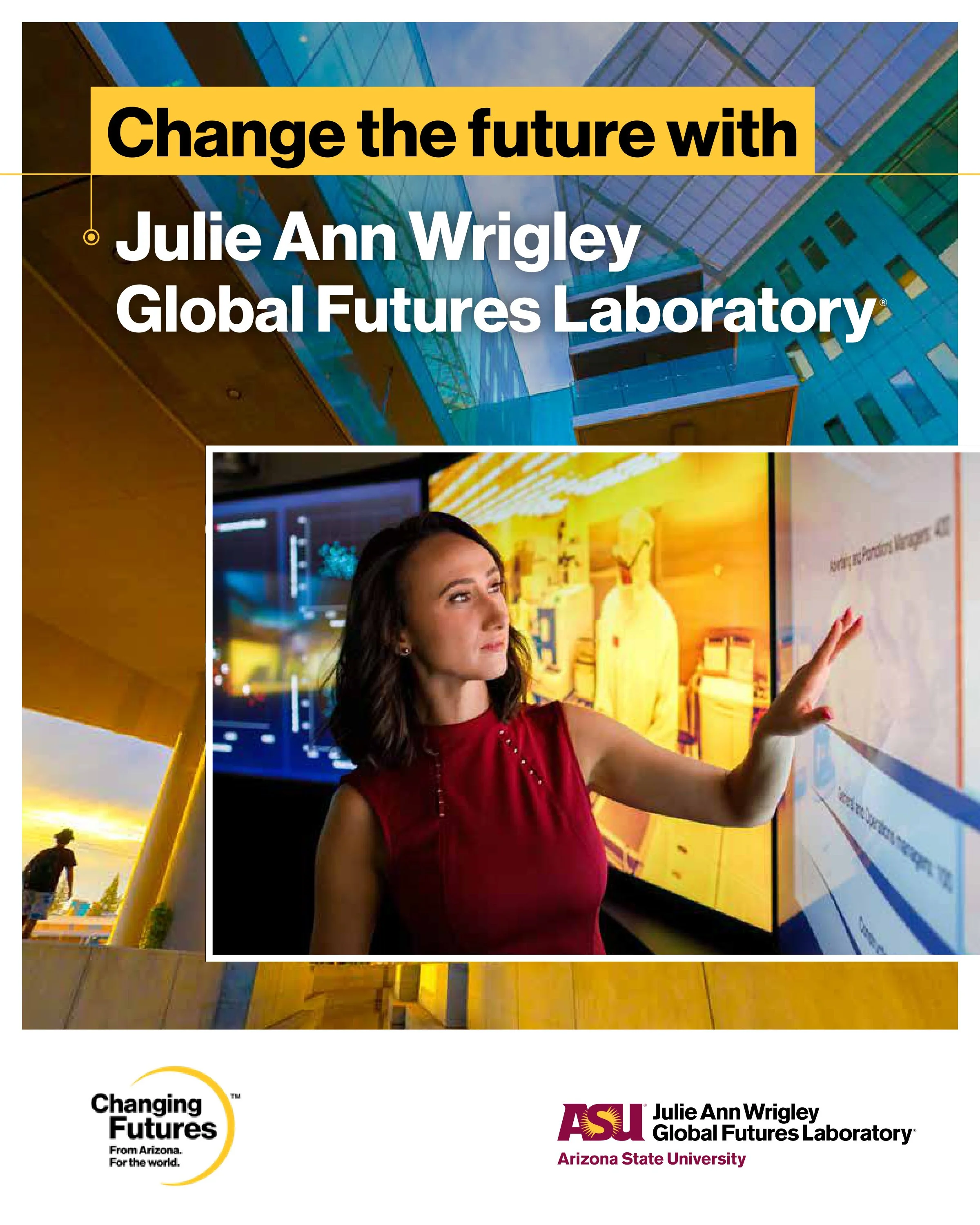 A woman with dark brown hair, in a red dress, is pointing at a large digital display in a modern room with colorful lighting. The display features diagrams and text. The background includes a large digital screen, abstract yellow structures, and peop