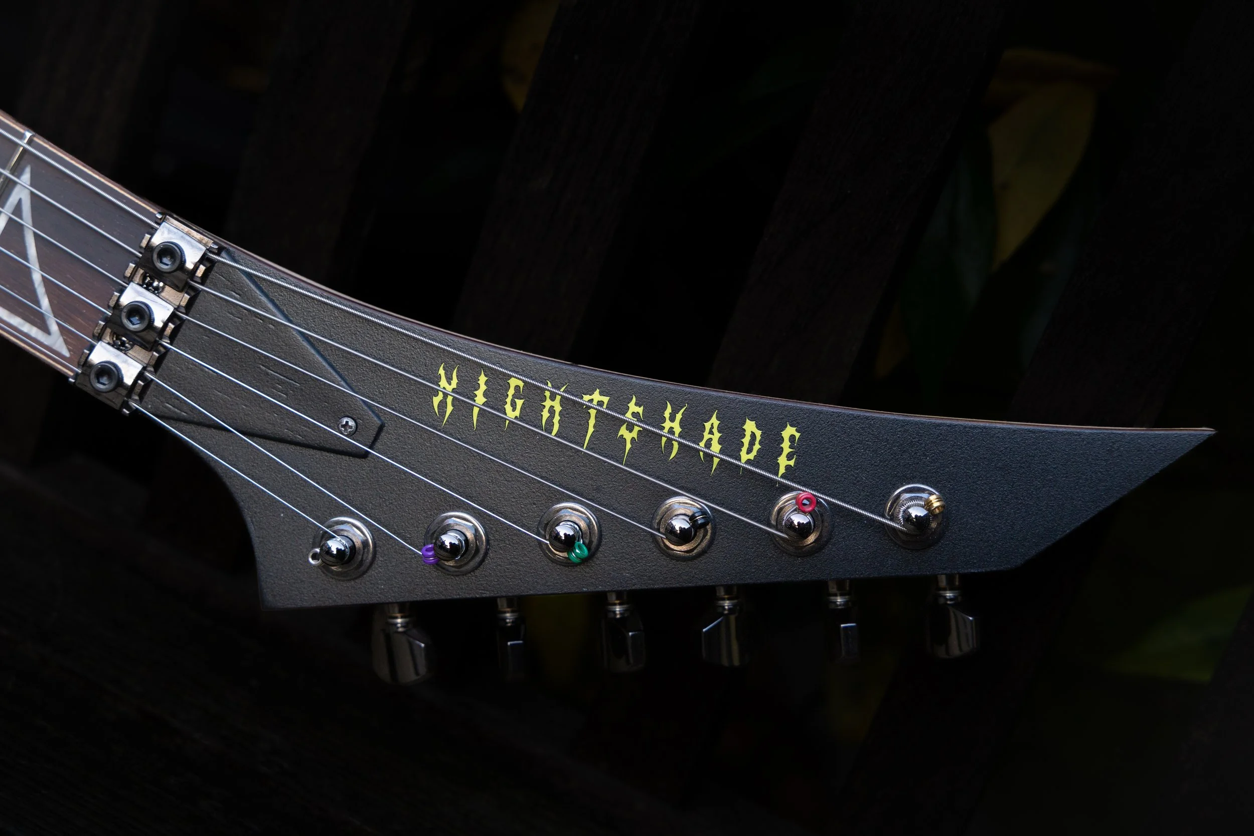 Close-up of an electric guitar headstock with tuning pegs and partially visible headstock with the text 'HIGHTIDE' in yellow font.