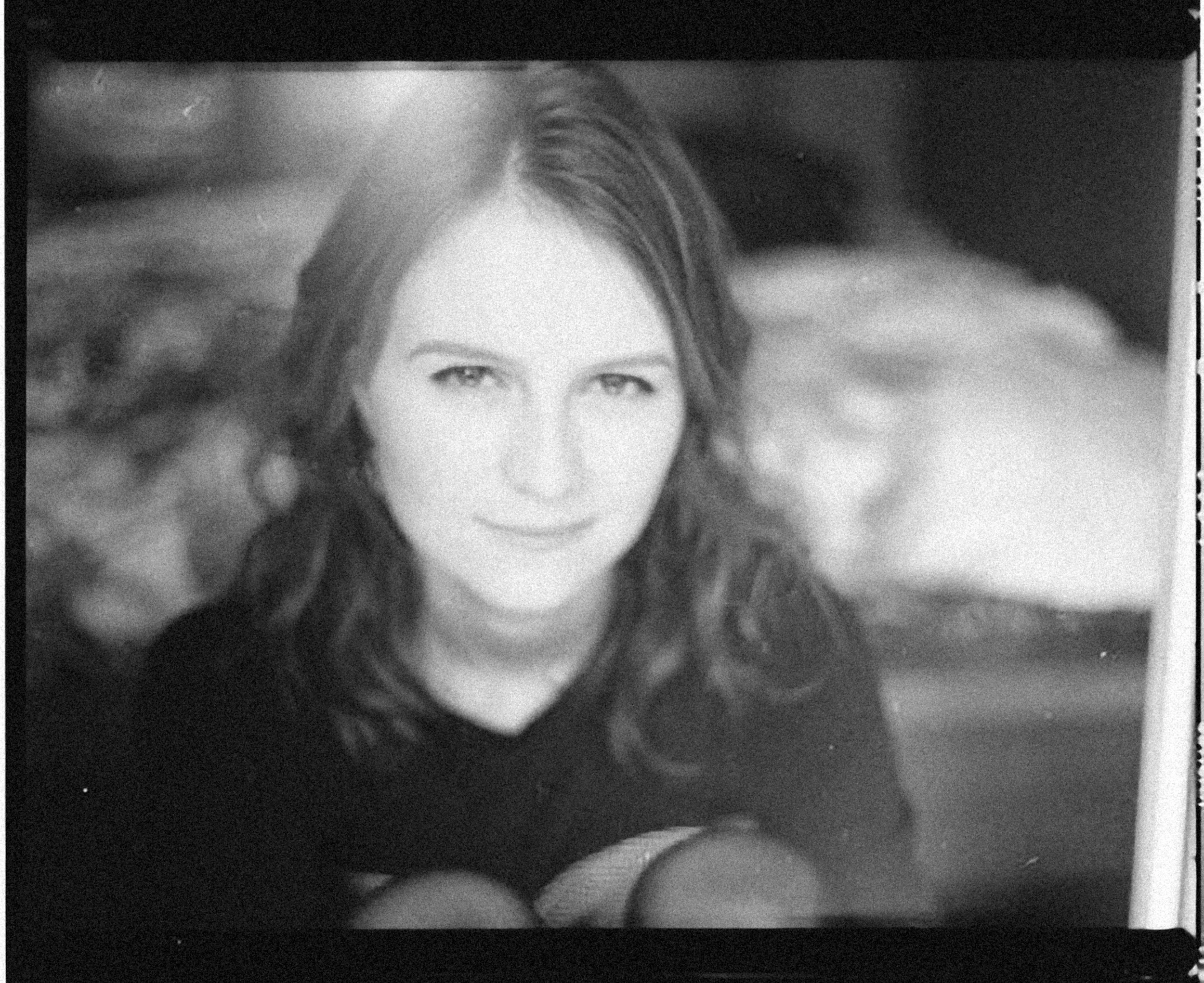 Black and white photograph of a woman with wavy hair, smiling softly and looking directly at the camera.