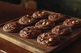A tray of freshly baked chocolate chip cookies on a wooden surface.