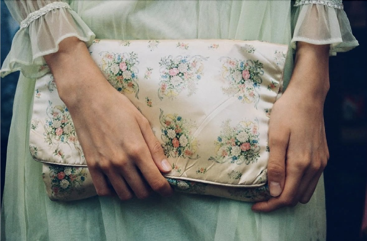 Person holding a floral-patterned pillow or cushion with both hands.