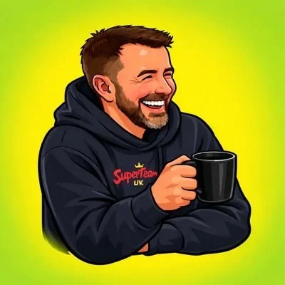 A man with short brown hair and a beard smiling while holding a black coffee mug, wearing a dark hoodie with 'SuperTeam UK' printed on it, against a green and yellow background.