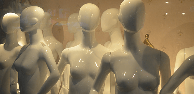 A display of white mannequin figures in a store window.