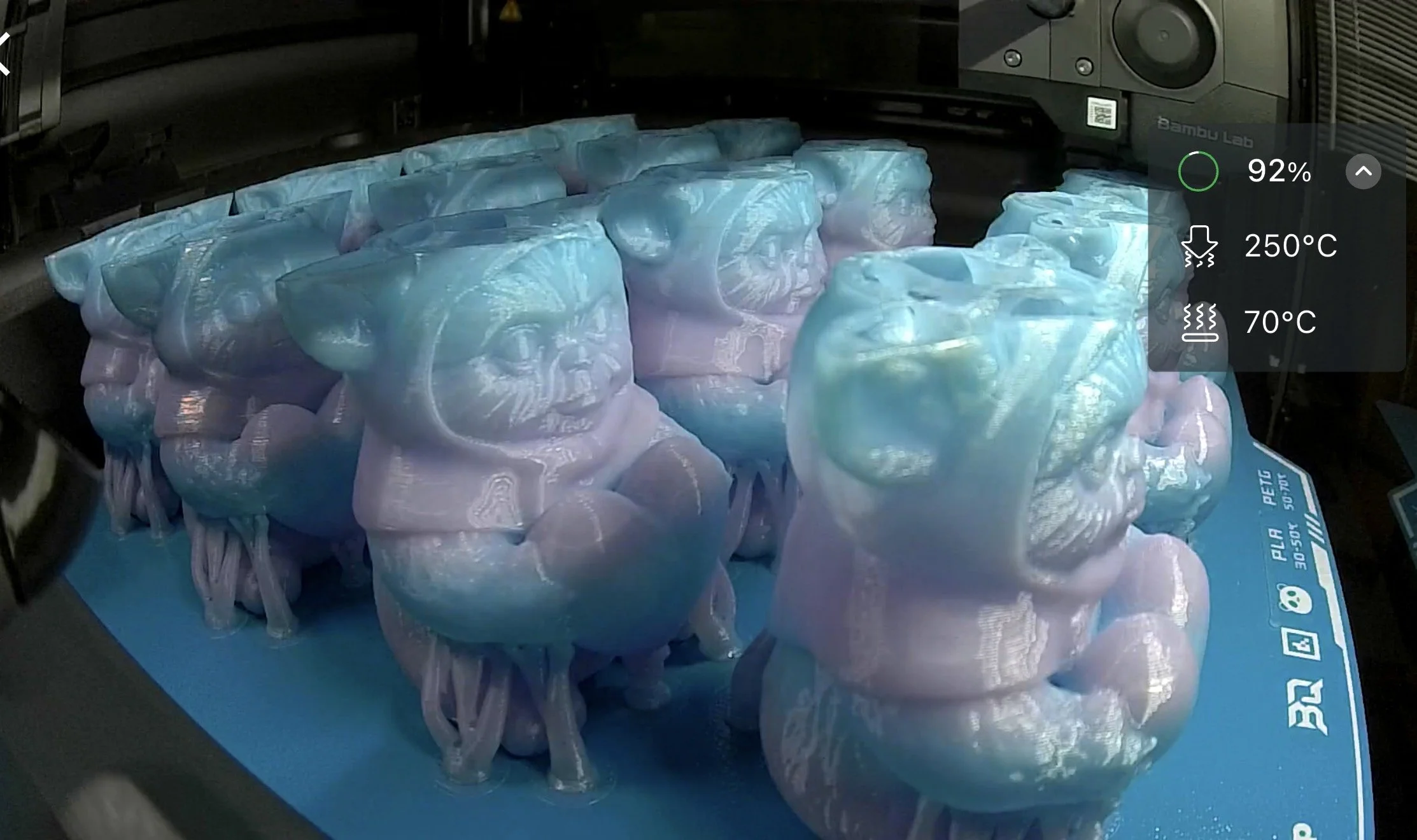 Close-up of a 3D printer printing blue and white filament into a sculpture or object.