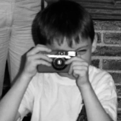Child holding a camera and taking a photograph.